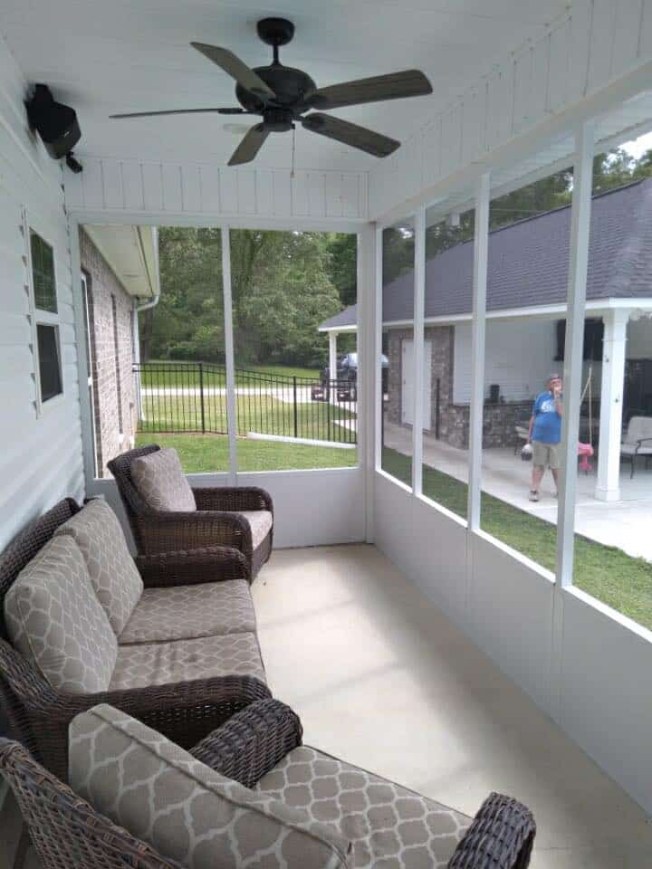 Inside a screen room with wicker furniture and a ceiling fan